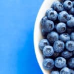 Blueberries In White Bowl On Colorful Blue Backround