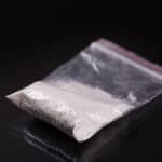 heroin in plastic packet on black background, closeup