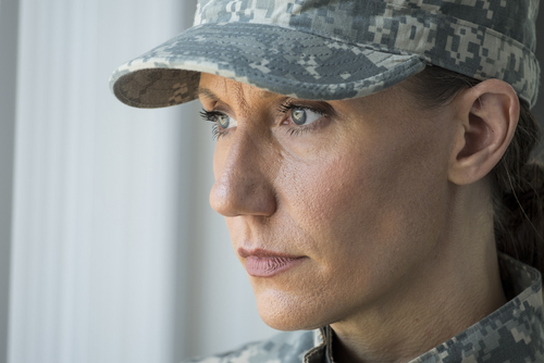 Female Veteran looking out window with serious look on face